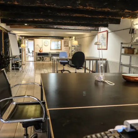 Kantoorruimte huren op Prinseneiland 23A in Amsterdam Centrum met houten balkenplafond en moderne meubels, geschikt voor verschillende werkactiviteiten.