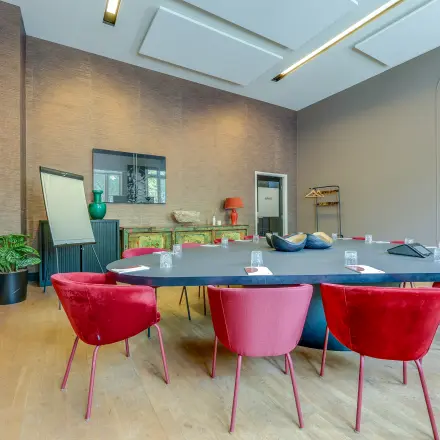 Stijlvolle vergaderruimte in het kantoorpand op Raamplein 1, Amsterdam Centrum, met een grote ovale tafel en moderne rode stoelen. Ideaal voor wie kantoorruimte wil huren.