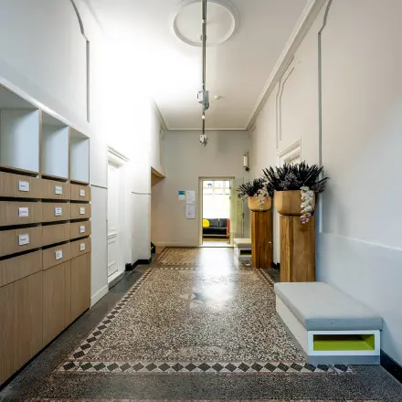 Ingang van een kantoorpand aan de Rapenburgerstraat 173 in Amsterdam Centrum, met strakke muren en een stijlvolle vloer. Ideaal voor bedrijven die kantoorruimte willen huren.