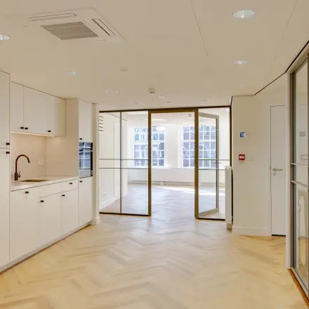 Lichte en moderne kantoorruimte op Rokin 117 117 Amsterdam Centrum met houten vloer, glazen scheidingswanden en een kleine pantry. Ideaal voor wie een kantoorpand wil huren.