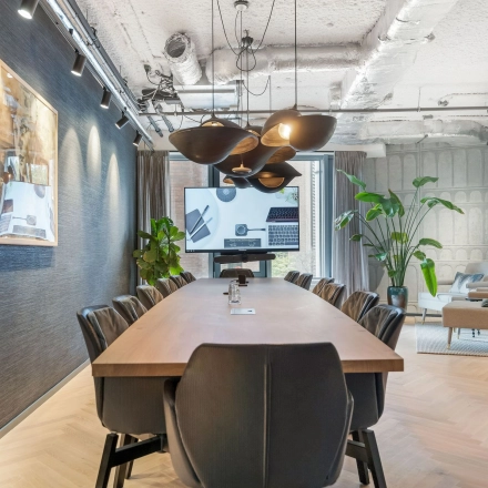 Stijlvolle vergaderruimte in kantoorpand Stadhouderskade 55 te Amsterdam Centrum, met lange houten tafel, moderne stoelen en grote schermen, ideaal om kantoorruimte te huren.