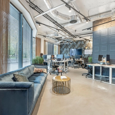 Moderne en lichte kantoorruimte aan de Stadhouderskade 55, Amsterdam Centrum, met werkplekken, bank en grote ramen. Personen voeren zakelijke activiteiten uit aan bureaus.