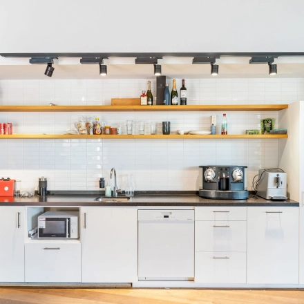 Gezellige pantry in een kantoorpand op Stadhouderskade 55, Amsterdam Centrum. Voorzien van moderne apparatuur en open schappen. Ideaal voor wie kantoorruimte wil huren.