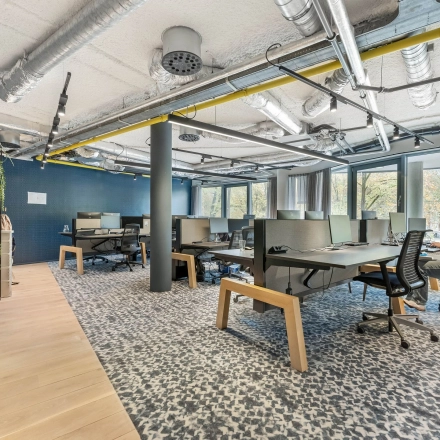 Moderne kantoorruimte huren op Stadhouderskade 55 in Amsterdam Centrum met open werkplekken, blauw interieur en grote ramen.