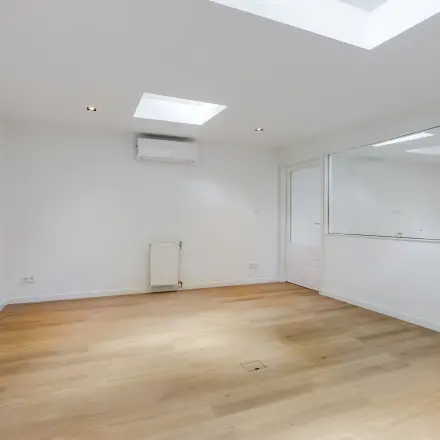 Lichte kantoorruimte met houten vloer en wit geverfde wanden op Schinkelkade 44, Amsterdam De Schinkel. Voorzien van luchtvering en groot raam.
