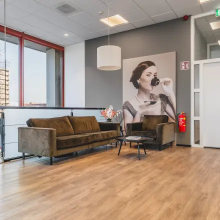 Stijlvolle kantoorruimte huren op Daalwijkdreef 47 in Amsterdam Duivendrecht met een moderne loungehoek en een grote afbeelding van een elegante dame aan de muur.