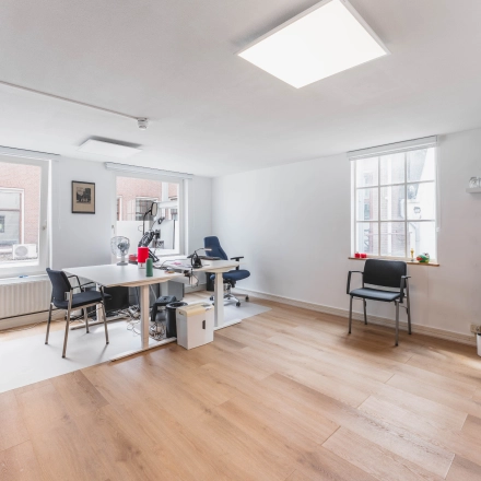 Een lichte, gemeubileerde kantoorruimte aan de Herengracht 221 in Amsterdam Grachtengordel met moderne bureaus en stoelen. Ideaal voor wie een kantoor wil huren in een historisch pand.