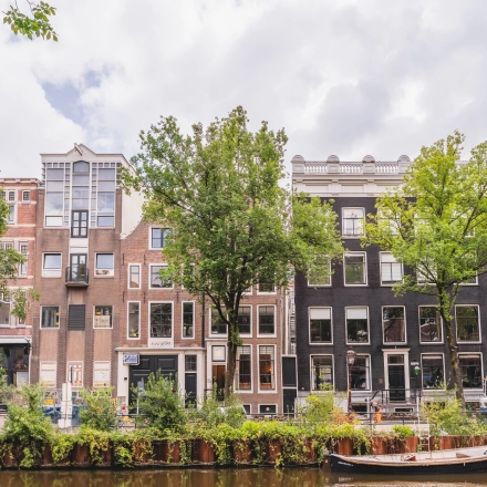 Buitenzicht op kantoorpand aan de Herengracht in Amsterdam Grachtengordel, met historische gevels en bomen langs de gracht.