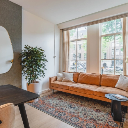 Gezellige kantoorruimte huren op Herengracht 221, Amsterdam Grachtengordel, met een comfortabele bank, een grote spiegel en een stijlvolle inrichting.