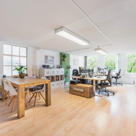 Kantoorruimte op Herengracht 221 in Amsterdam Grachtengordel, een lichte en gemeubileerde werkruimte met houten tafels en moderne bureaus voor huur.