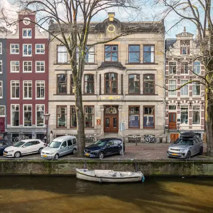 Historisch kantoorpand aan de Herengracht 320 in Amsterdam Grachtengordel, met klassieke gevel aan de gracht, omgeven door geparkeerde auto's en fietsen.