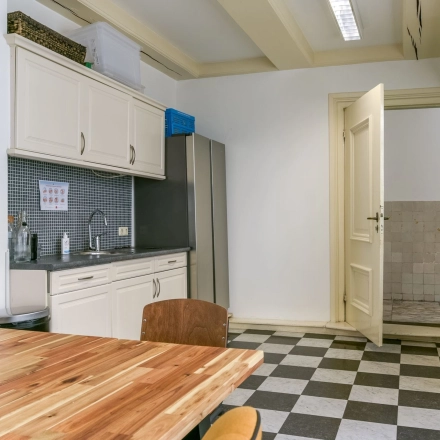 Kantoorpand aan de Herengracht 338 in Amsterdam Grachtengordel met een gemeubileerde keukenruimte. Ideaal voor kantoorruimte huren, voorzien van een tafel, stoelen, keukenblok en koelkast.
