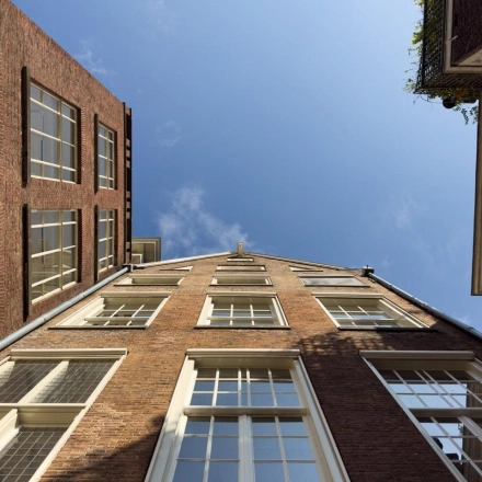 Gevel van een kantoorpand aan de Herengracht 582-584 in Amsterdam met bakstenen en grote ramen onder een heldere lucht.