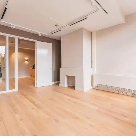 Lege kantoorruimte met houten vloer en neutrale muren, geschikt voor kantoorinrichting, gelegen aan Herengracht 582-584 in Amsterdam Grachtengordel.