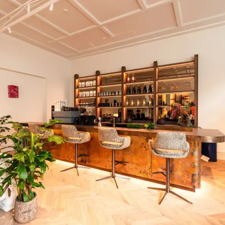 Modern ingerichte lounge met een stijlvolle bar, planten en comfortabele zitjes in een kantoorpand aan de Keizersgracht 264 in Amsterdam Grachtengordel. Kantoorruimte huren met een eigentijdse uitstraling.