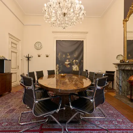 Kantoorruimte huren aan de Keizersgracht 391A in Amsterdam Grachtengordel met een elegante conferentieruimte, een houten tafel, moderne stoelen en een klassieke kroonluchter.