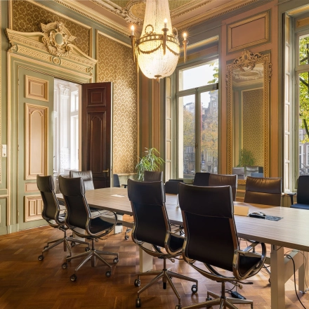 Kantoorruimte huren aan de Keizersgracht 452 in Amsterdam Grachtengordel met klassieke inrichting en chique vergadertafel met zwarte stoelen, omringd door elegante houtpanelen en grote ramen.