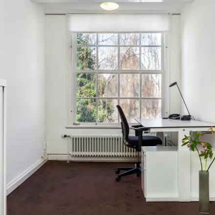 Heldere kantoorruimte met groot raam aan de Keizersgracht 62-64 in Amsterdam Grachtengordel, voorzien van een bureau en stoel, ideaal om als kantoor te huren.