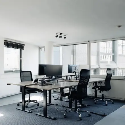 Lichte kantoorruimte huren op Weesperstraat 394-396 in Amsterdam Grachtengordel met bureaus, stoelen en computers klaar voor gebruik in een moderne setting.