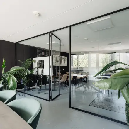 Moderne kantoorruimte in Amsterdam Grachtengordel aan de Weesperstraat 394-396, met glazen wanden, groene planten en stijlvolle meubilair. Ideale plek voor creatief werken en huren.