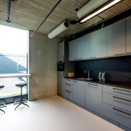 Moderne pantry in kantoorpand aan de Moermanskkade 109-113, Amsterdam Houthavens, met veel opbergruimte, strakke keukenapparatuur en uitzicht op een buitenzitje. Ideaal voor een kantoorruimte huren.