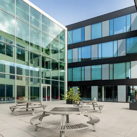 Ruime binnenplaats van het kantoorpand op Pedro de Medinalaan 1-9, Amsterdam IJburg, met moderne glazen gevels en meerdere zitplekken, ideaal voor bedrijven die kantoorruimte willen huren.