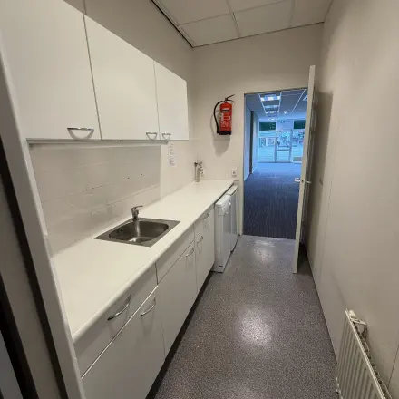Compacte pantry met witte keukenkasten en een enkele gootsteen, ideaal voor een kantoorruimte huren in het kantoorpand op Buikslotermeerplein 430, Amsterdam Noord.