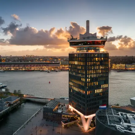 Panoramisch uitzicht op het kantoorgebouw aan Overhoeksplein 1 in Amsterdam Noord, gelegen aan het water met een indrukwekkend stadsgezicht op de achtergrond.