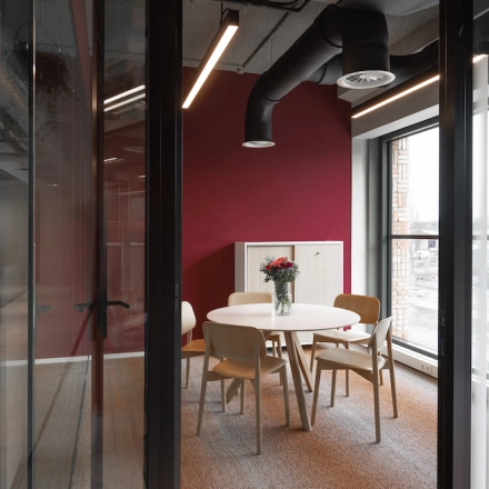 Moderne kantoorruimte op Papaverhof 58 in Amsterdam Noord met een ronde tafel en stoelen, ideaal voor vergaderingen. Grote ramen zorgen voor veel natuurlijk licht.