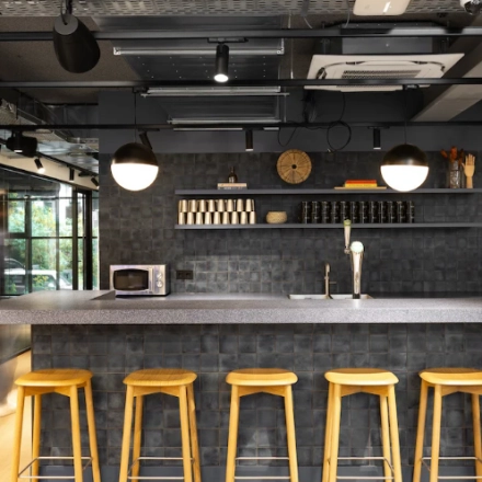 Stijlvolle en moderne kantoorruimte in Amsterdam Noord met een strakke bar en hoge krukken. Ideaal voor huur als onderdeel van een kantoor met voorzieningen in het kantoorpand.