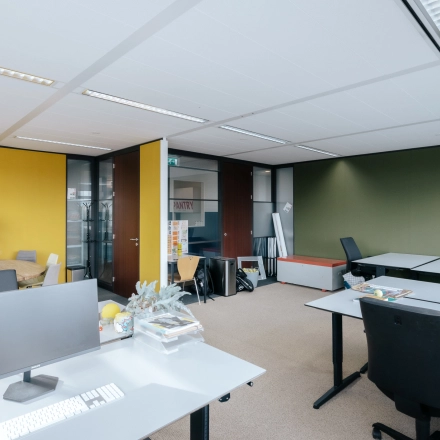 Kantoorruimte in Amsterdam Noord op TT Vasumweg 44 met bureaus, computers en een gele muur.