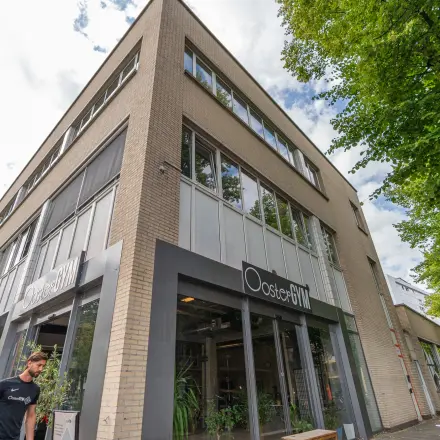 Het kantoorpand op James Wattstraat 71 in Amsterdam Oost toont een moderne gevel met grote ramen en groene beplanting aan de buitenzijde.