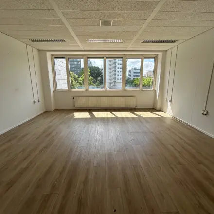Ongemeubileerde kantoorruimte op James Wattstraat 71, Amsterdam Oost met uitzicht op de stad. Ruimte in een kantoorpand met grote ramen en houten vloer, ideaal om te huren voor een open werkplek.