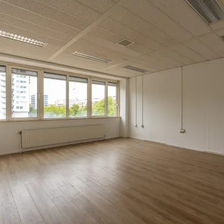 Leegstaande kantoorruimte te huur op James Wattstraat 71 in Amsterdam Oost, met grote ramen en een houten vloer. Ideaal voor een frisse start in een dynamische omgeving.
