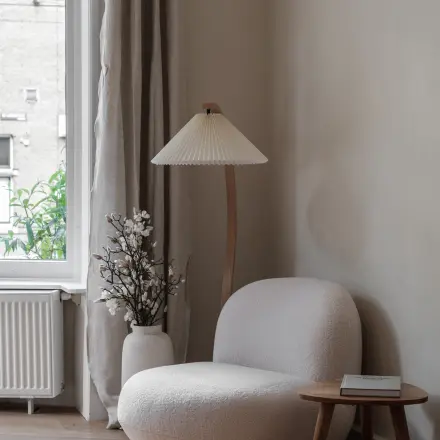 Stijlvolle hoek van een kantoor aan de Emmalaan 7-9 in Amsterdam Oud Zuid, met een comfortabele stoel, bijzettafel en een lamp naast een groot raam.