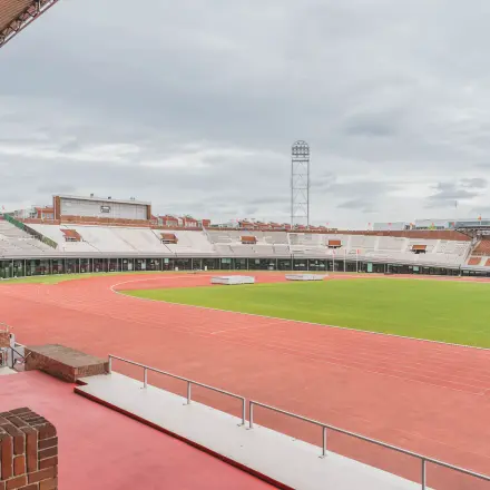Buitenaanzicht van het Olympisch Stadion in Amsterdam met omringende atletiekbaan, ideaal als locatie voor evenementen of kantoorruimte huren.