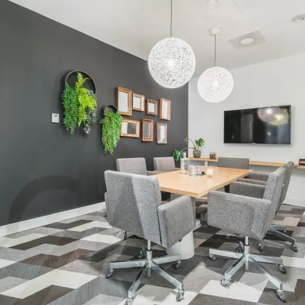 Moderne vergaderruimte in kantoorpand Olympisch Stadion 24-28, Amsterdam Oud Zuid, met grijze stoelen rond een houten tafel, hangplanten en een flatscreen aan de muur. Kantoorruimte huren.