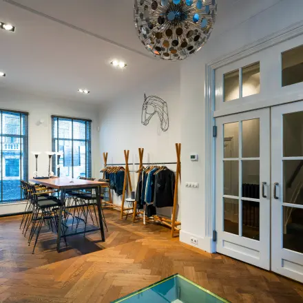 Interieur van een kantoor op PC Hooftstraat 150 in Amsterdam Oud Zuid, met een houten vloer, moderne verlichting en kantoormeubilair. Huur deze kantoorruimte in een stijlvol kantoorpand.