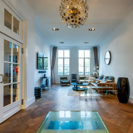 Stijlvolle kantoorruimte huren op PC Hooftstraat 150, Amsterdam Oud Zuid, met houten vloer, moderne inrichting en grote ramen, ideaal voor zakelijke ontmoetingen.