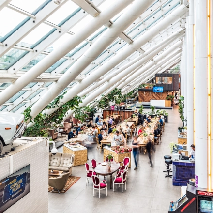 Ruime en lichte kantoor met glazen dak op Johan Huizingalaan 400, Amsterdam Riekerpolder, vol met mensen die samenwerken aan tafels.