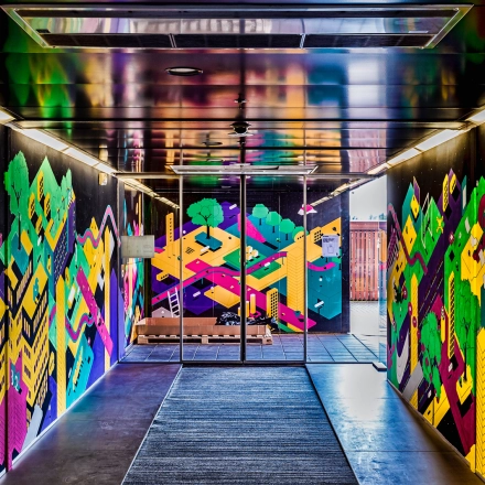 Ingang van het kantoorpand op Johan Huizingalaan 400, Amsterdam Riekerpolder, met kleurrijke muurschilderingen. Ideale plek voor bedrijven die kantoorruimte zoeken in een inspirerende omgeving.
