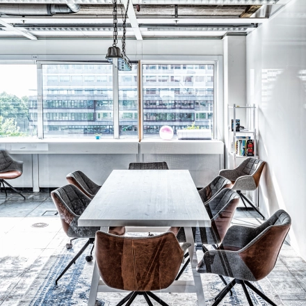 Kantoorruimte huren aan de Johan Huizingalaan 400, Amsterdam Riekerpolder. Moderne werkruimte met grote ramen, industrieel plafond en een grote tafel met zes stoelen. Veel daglicht, ideaal voor vergaderingen.