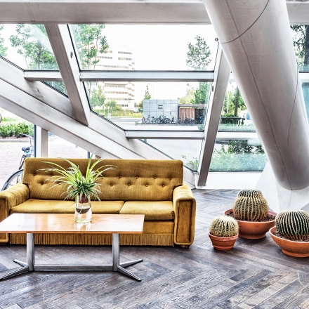 Moderne kantoorruimte met grote ramen op Johan Huizingalaan 400 in Amsterdam Riekerpolder, met comfortabele zitplaatsen en planten. Ideaal voor wie een creatieve werkruimte wil huren.