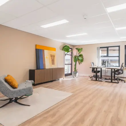 Ruime kantoorruimte huren in Amsterdam Sloterdijk aan Arlandaweg 92 met moderne meubels, bureaus en een grote plant, geschikt voor werk en vergaderingen.