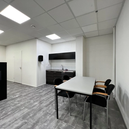 Moderne kantoorruimte huren aan de Contactweg 131 in Amsterdam Sloterdijk, met strakke vloeren, witte muren en een kitchenette met stoelen, ideaal voor diverse zakelijke activiteiten.