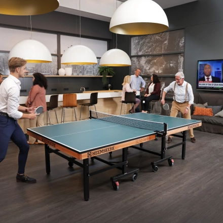 Grote kantoorruimte in Amsterdam Sloterdijk met mensen die tafeltennis spelen en anderen die bij de bar zitten en netwerken. Gezellige sfeer geschikt voor huur als creatieve werkruimte.