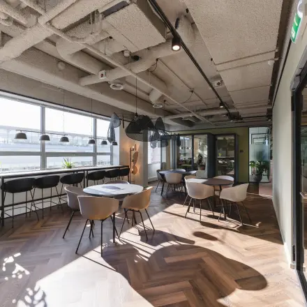 Moderne kantoorruimte met grote ramen, parketvloer en stijlvolle stoelen op Bos en Lommerplein 280, Amsterdam West. Ideaal om kantoorruimte te huren in een inspirerend kantoorpand.