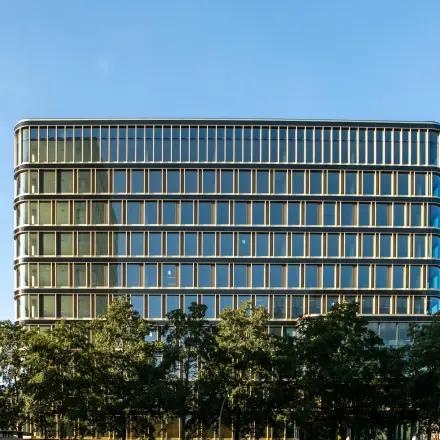 Modern kantoorpand aan het Kon. Wilhelminaplein 4 in Amsterdam West met glazen gevel en omliggende bomen, ideaal voor kantoorruimte huren.