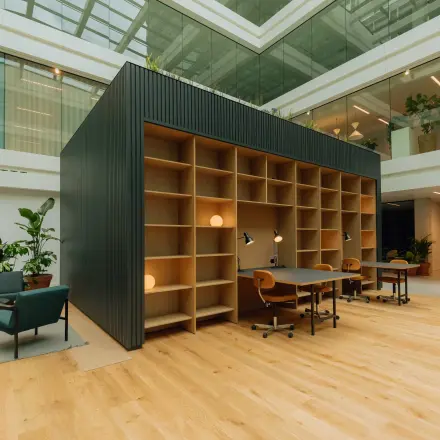 Moderne kantoorruimte aan Kon. Wilhelminaplein 4 in Amsterdam West met open werkruimte, licht houten vloer en grote ramen. Ruimte is deels gemeubileerd met bureaustoelen en tafels voor verhuur.