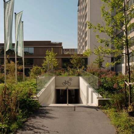 Ingang naar de ondergrondse fietsenstalling bij het kantoorpand op Nachtwachtlaan 20, Amsterdam West. Omgeven door groen en hoge gebouwen.